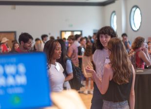 students chat in ballroom